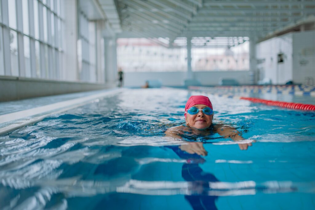 Active senior woman swimming in indoors swimming pool